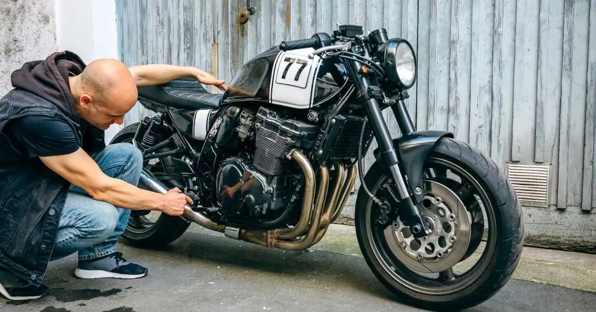 A rider crouched down checking the engine and exhaust before a ride