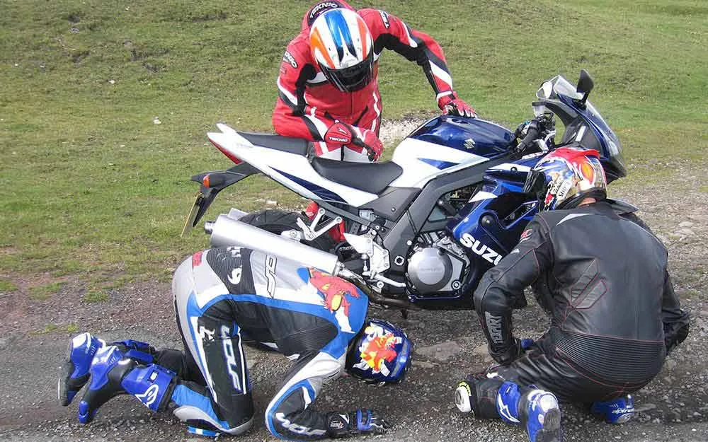 A rider checking the chain and rear wheel before setting off