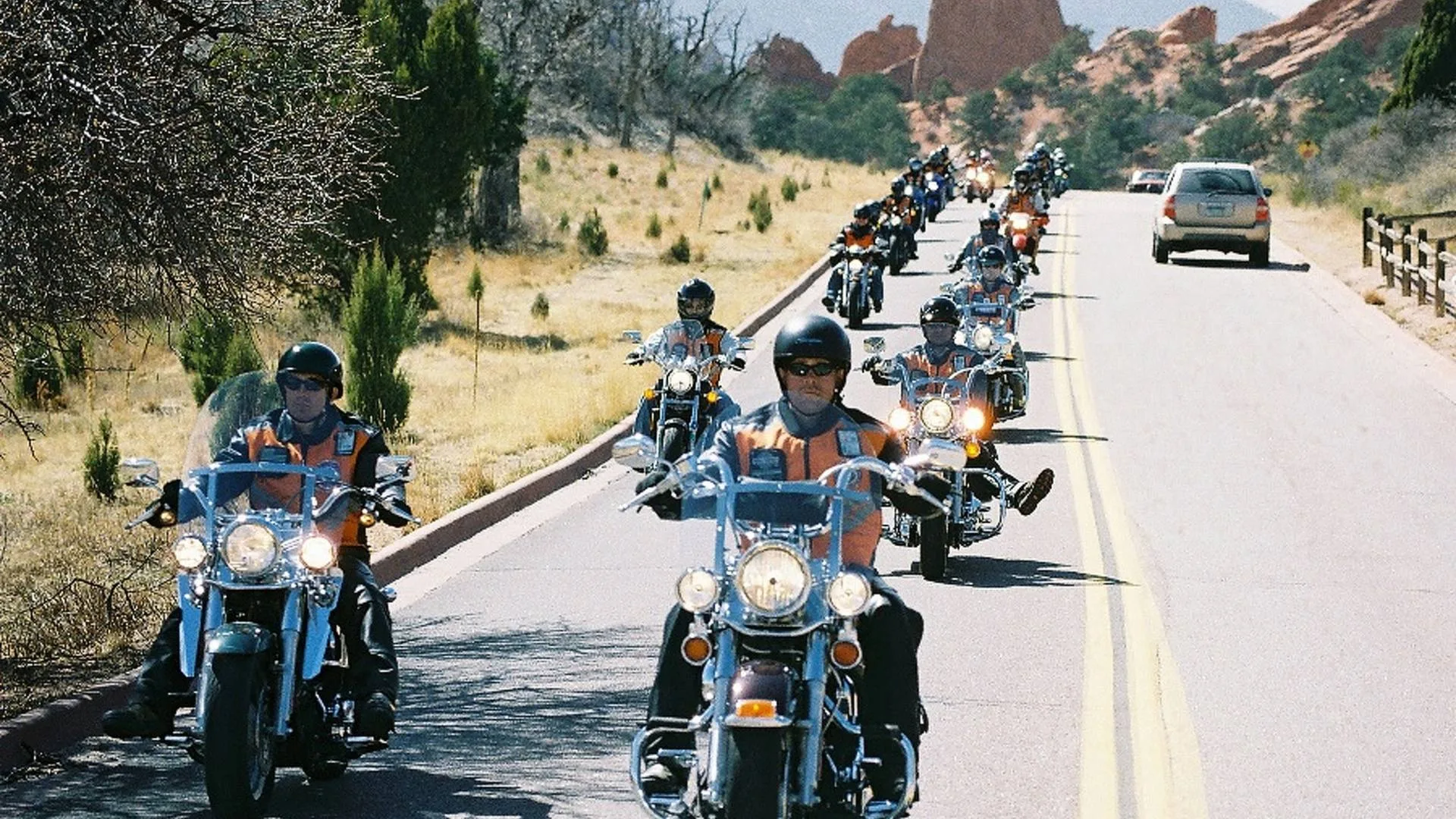 A long staggered formation of riders moving together along a highway